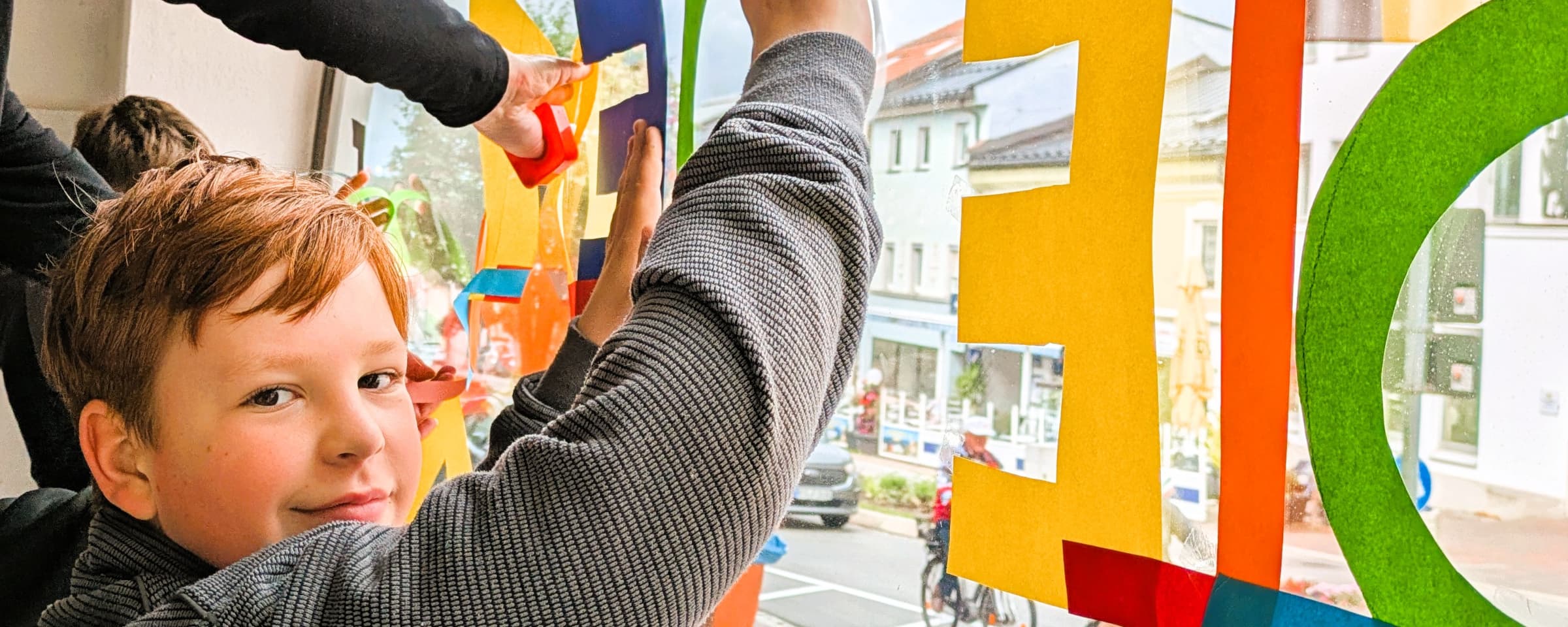 Schüler beim Anbringen der Schaufensterbeschriftung